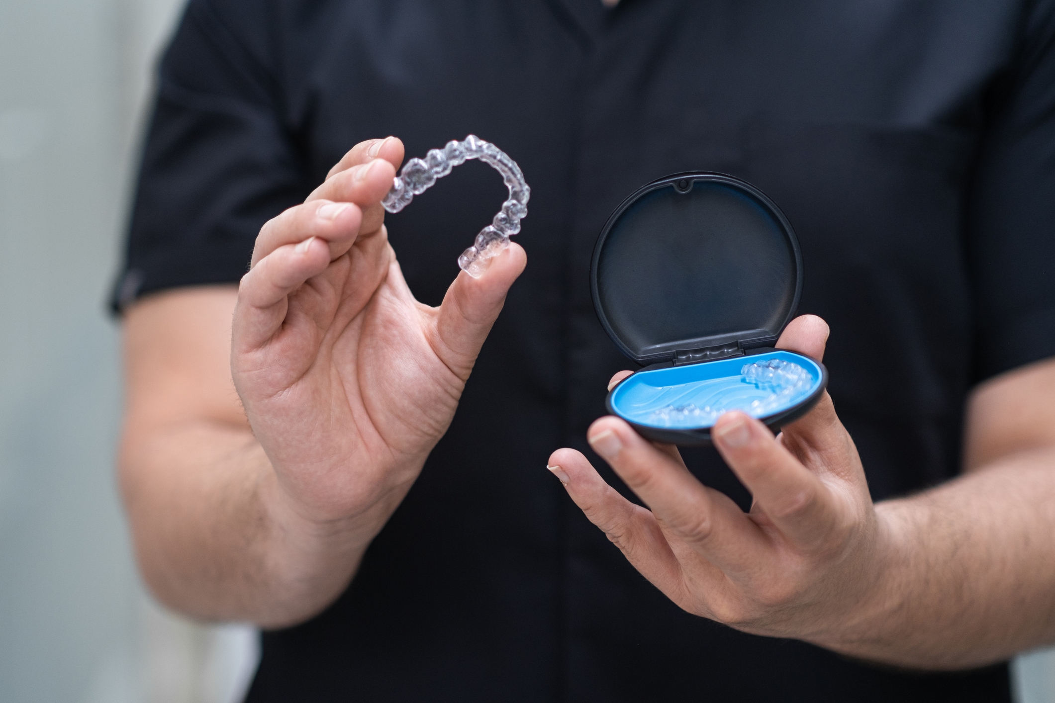 Orthodontist holding Invisalign clear aligners at Dream Smiles Dental in Bolton