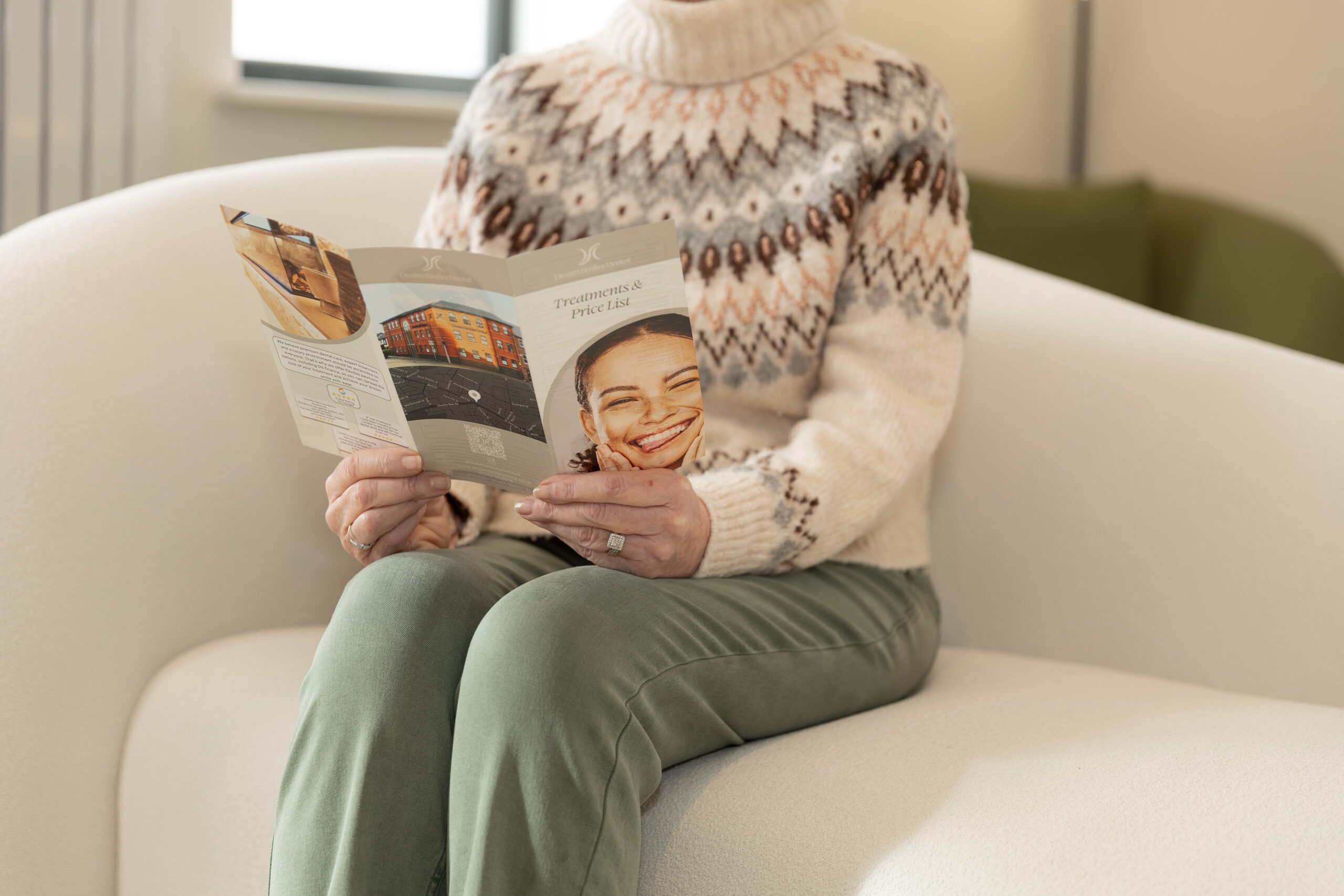Patient sitting comfortably in the Dream Smiles Dental waiting area reading price list